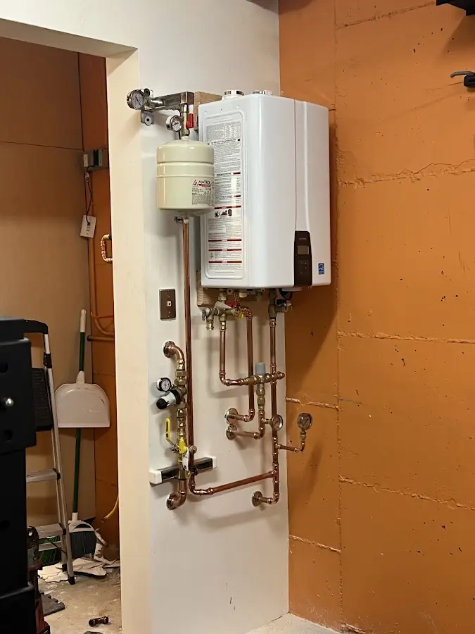 Plumbing technician inspecting water heater connections in Shaler